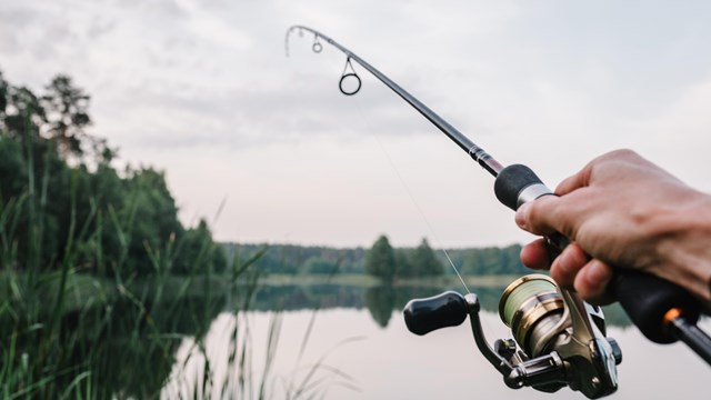 Bank fishing on the shores of Lake Roosevelt with trees in the distance.